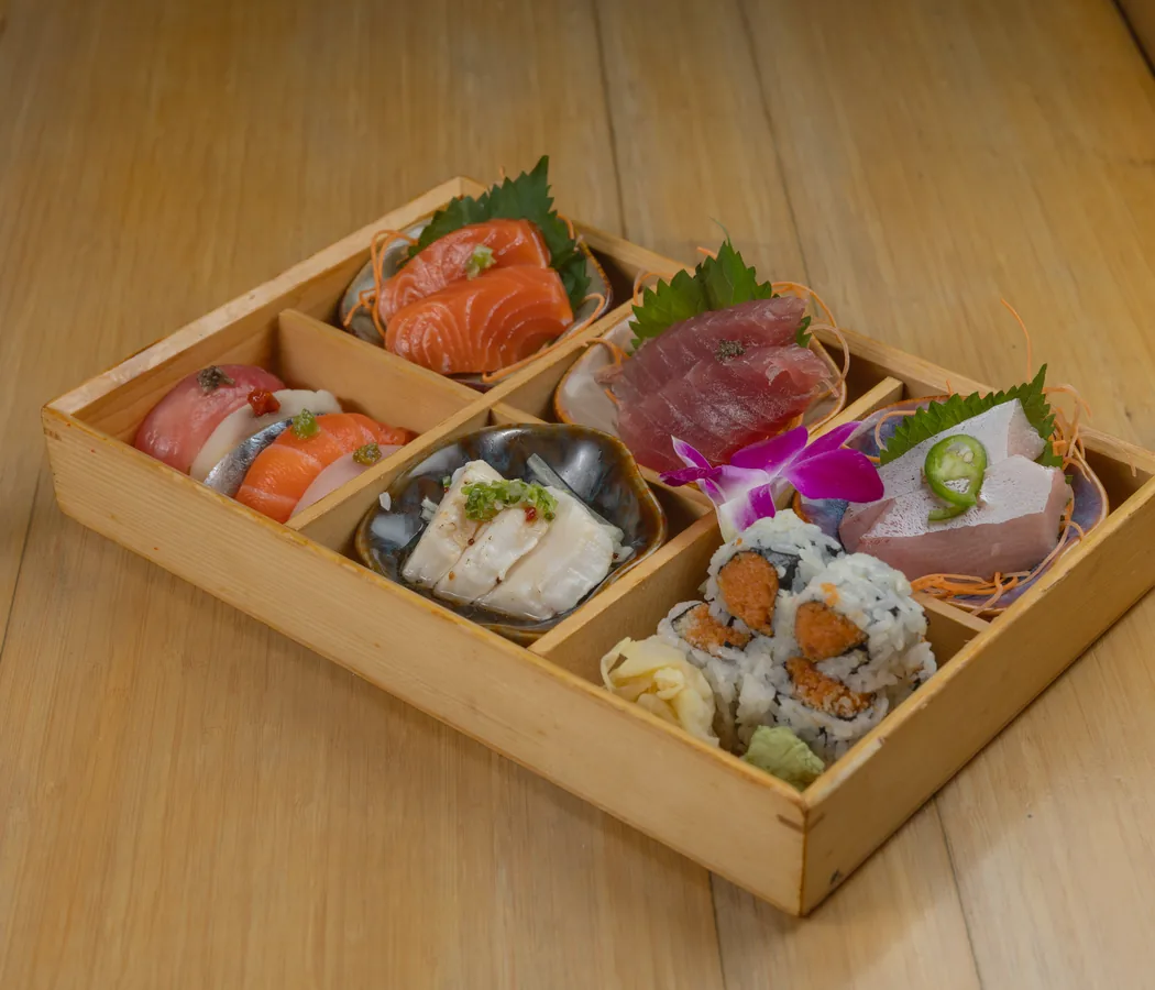 A wooden box of sashimi and sushi rolls