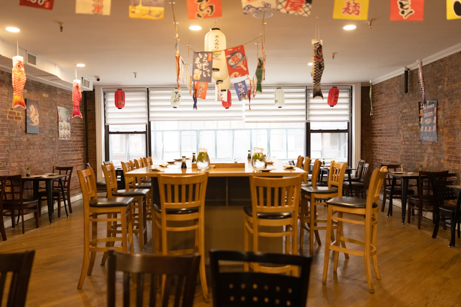 A bright dining room with a large shared table by the windows