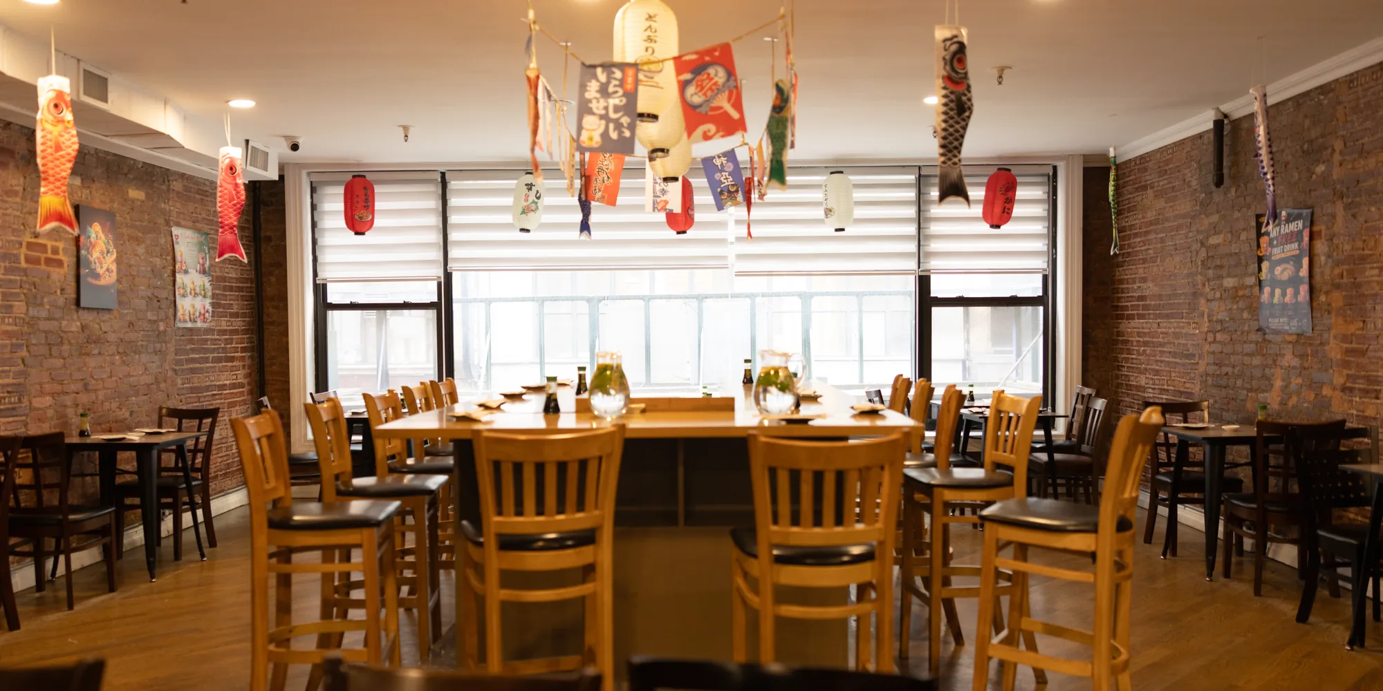 A bright dining room with a large shared table by the windows