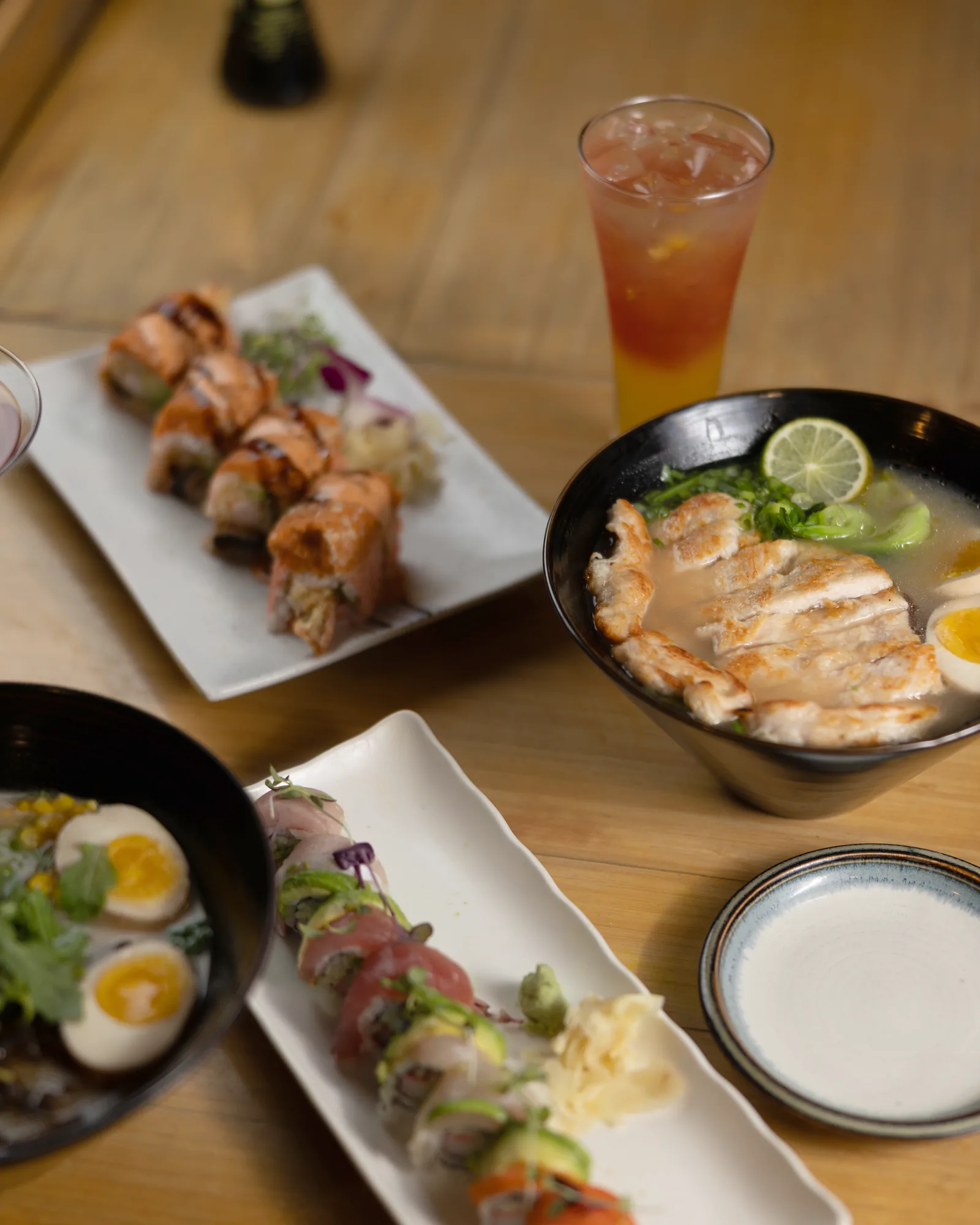 Ramen, sushi rolls and an iced drink shared across one table